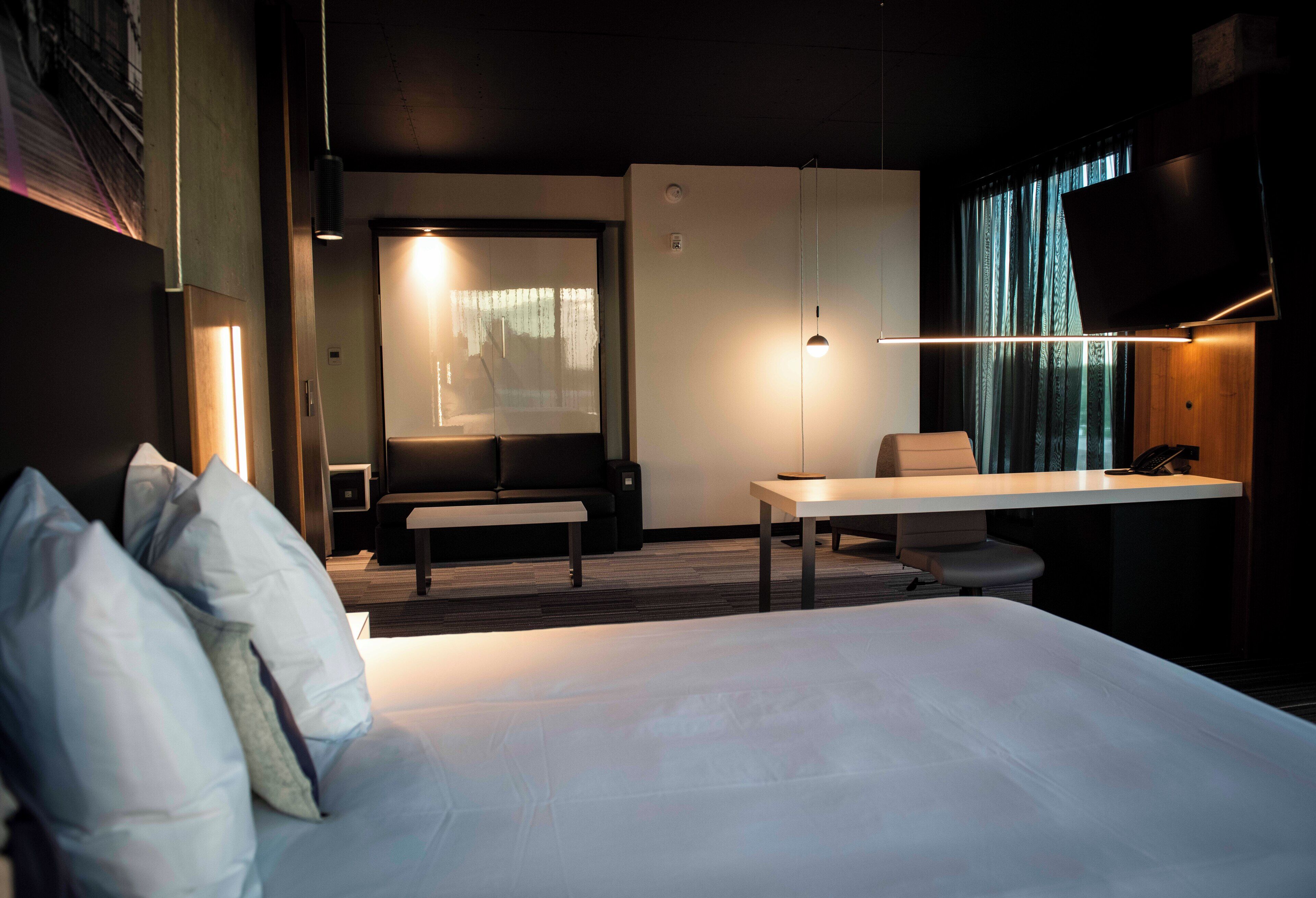 A modern hotel room with a large bed, a desk, and a television.