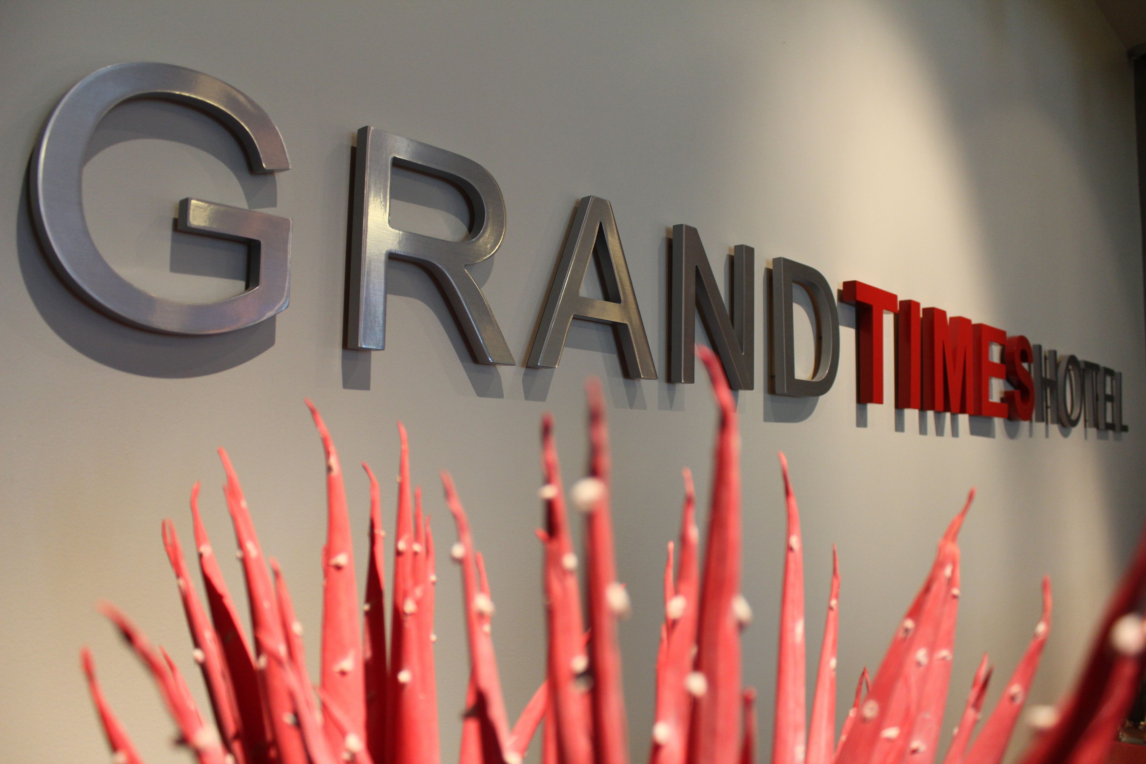 A wall with the words "GRAND TIMES HOTEL" in metallic letters.