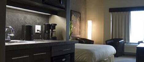 Una habitación de hotel con cama, escritorio, cafetera y ventana con cortinas.