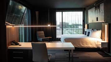 Une chambre d’hôtel équipée d’un lit, d’un bureau, d’une chaise et d’une grande fenêtre donnant sur un pont.