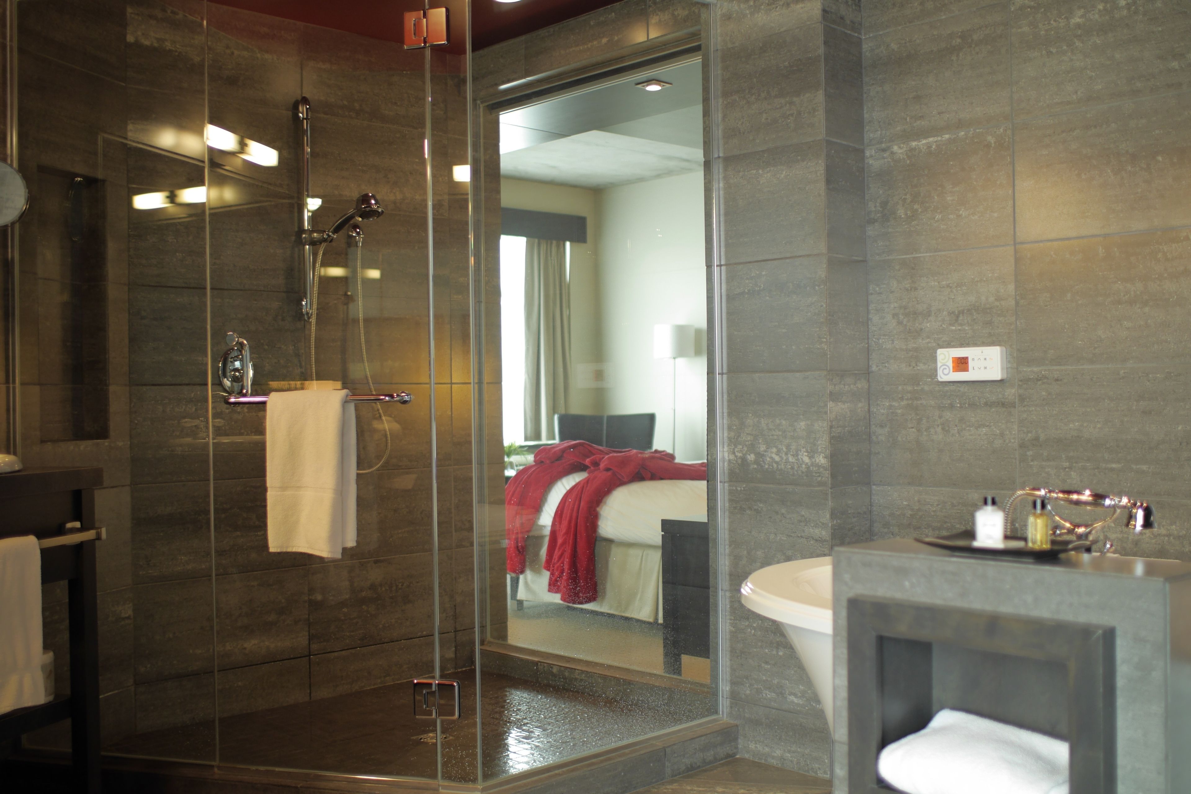 A modern bathroom with a glass-enclosed shower, a large mirror, and a separate sink area.