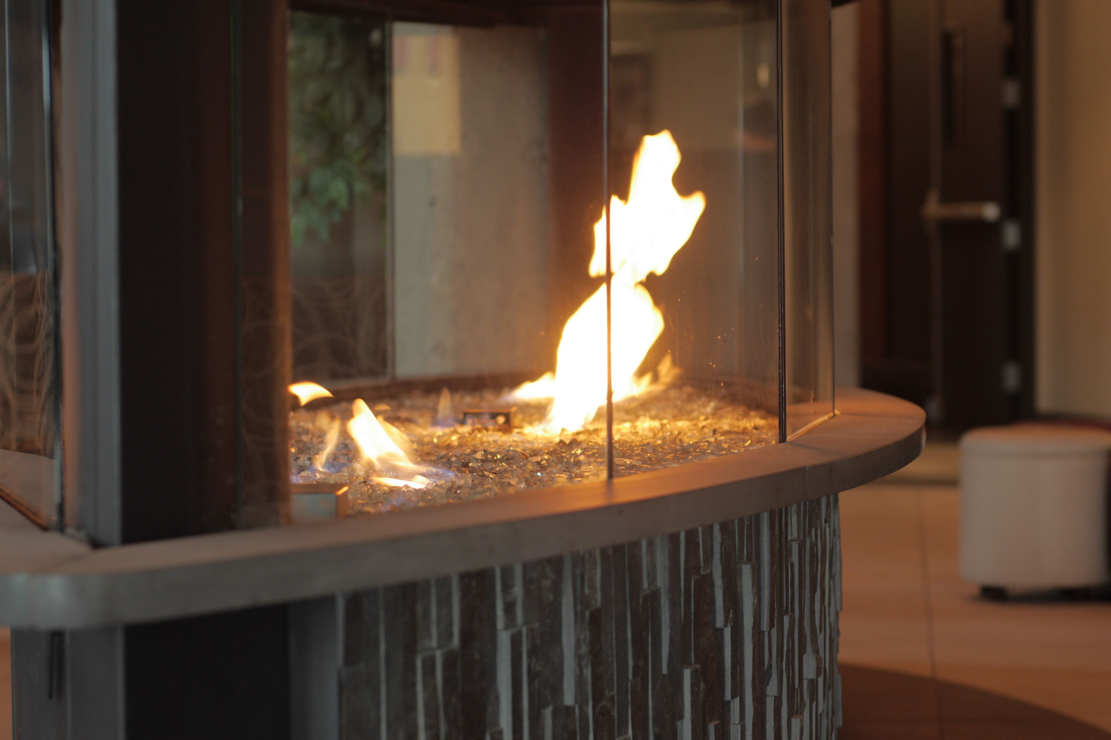 A glass-enclosed fire feature with visible flames, set in a modern stone structure.