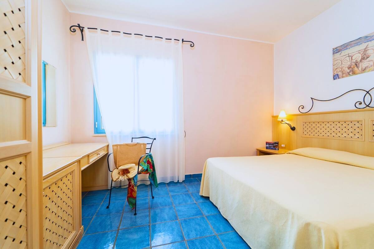 A bedroom with a bed, a desk, and a chair.