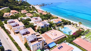 Un resort costero con varias edificaciones, una piscina y una playa.