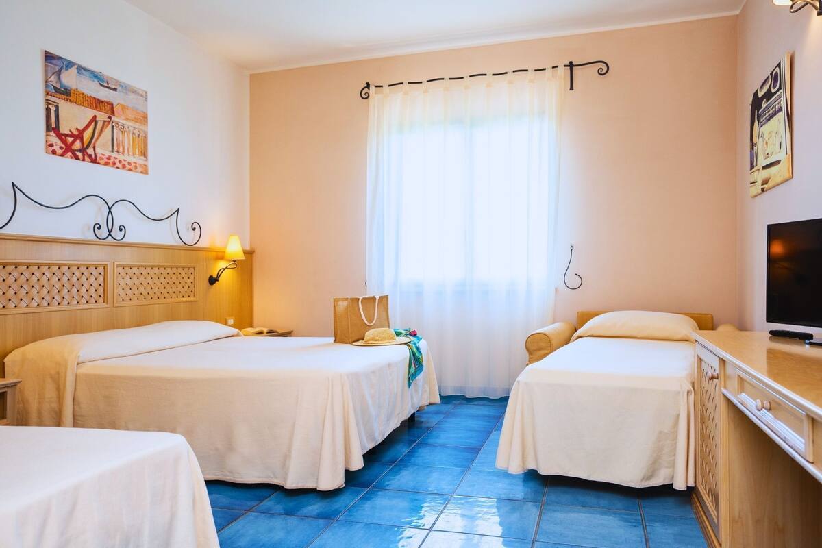 A hotel room with two beds, a TV, and a window with curtains.