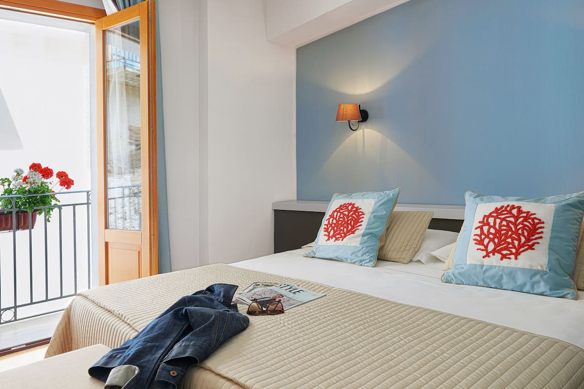 Une chambre à coucher avec un lit, une table de chevet, une fenêtre donnant sur un beau paysage et une lampe fixée au mur.