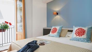 A hotel room with a bed, a nightstand, a wall-mounted lamp, and a balcony with flowers.