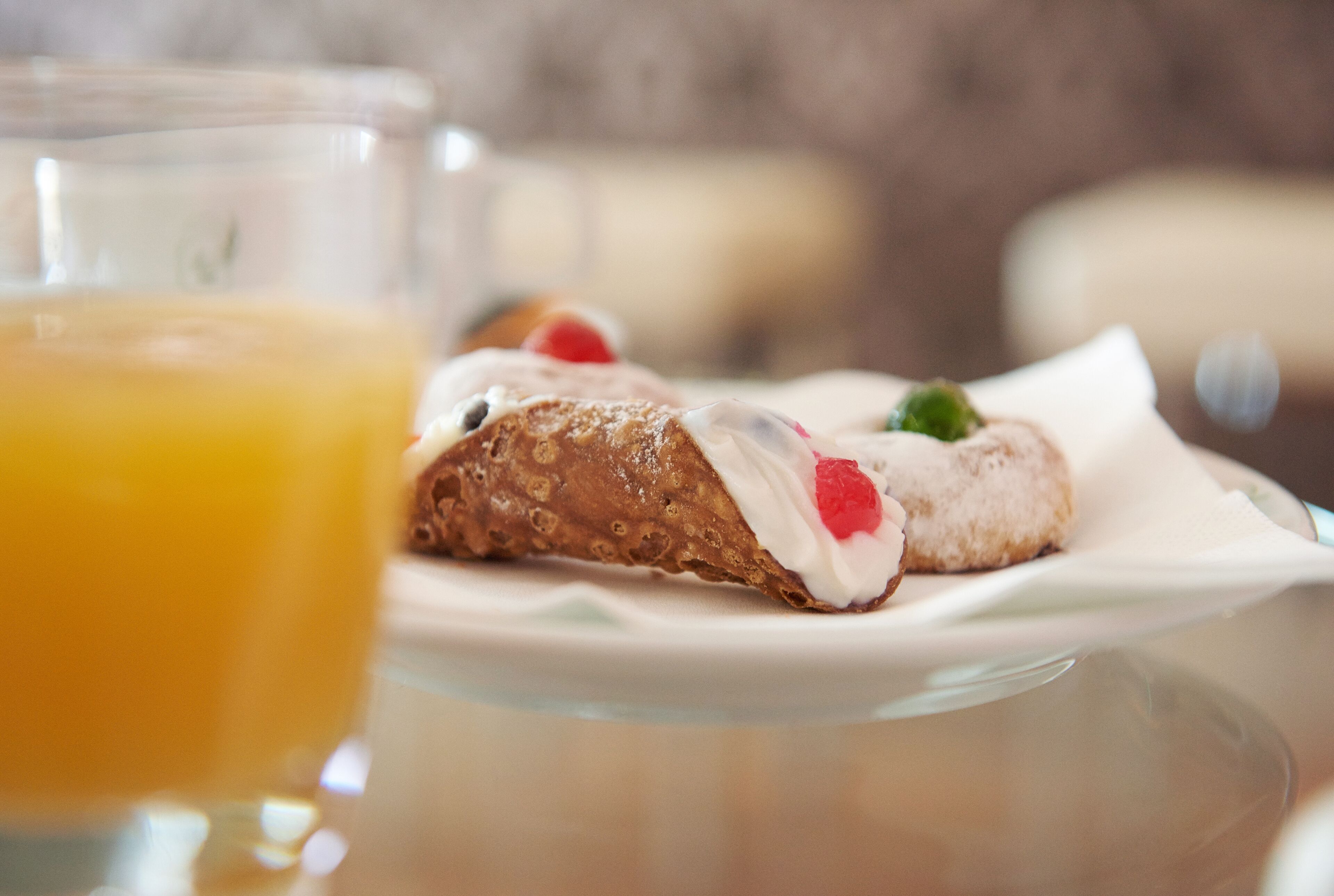 A dessert plate with a pastry and a glass of orange juice on a table.