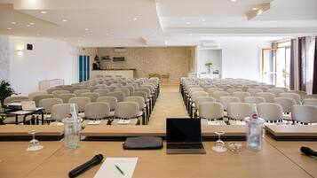 A conference room with rows of chairs, a podium, and tables with laptops and water bottles.