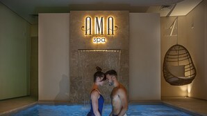 Un couple dans un bassin de spa, avec une pancarte indiquant « Spa AMA » au-dessus.