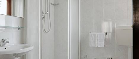 A bathroom with a glass-enclosed shower, a pedestal sink, and a toilet.