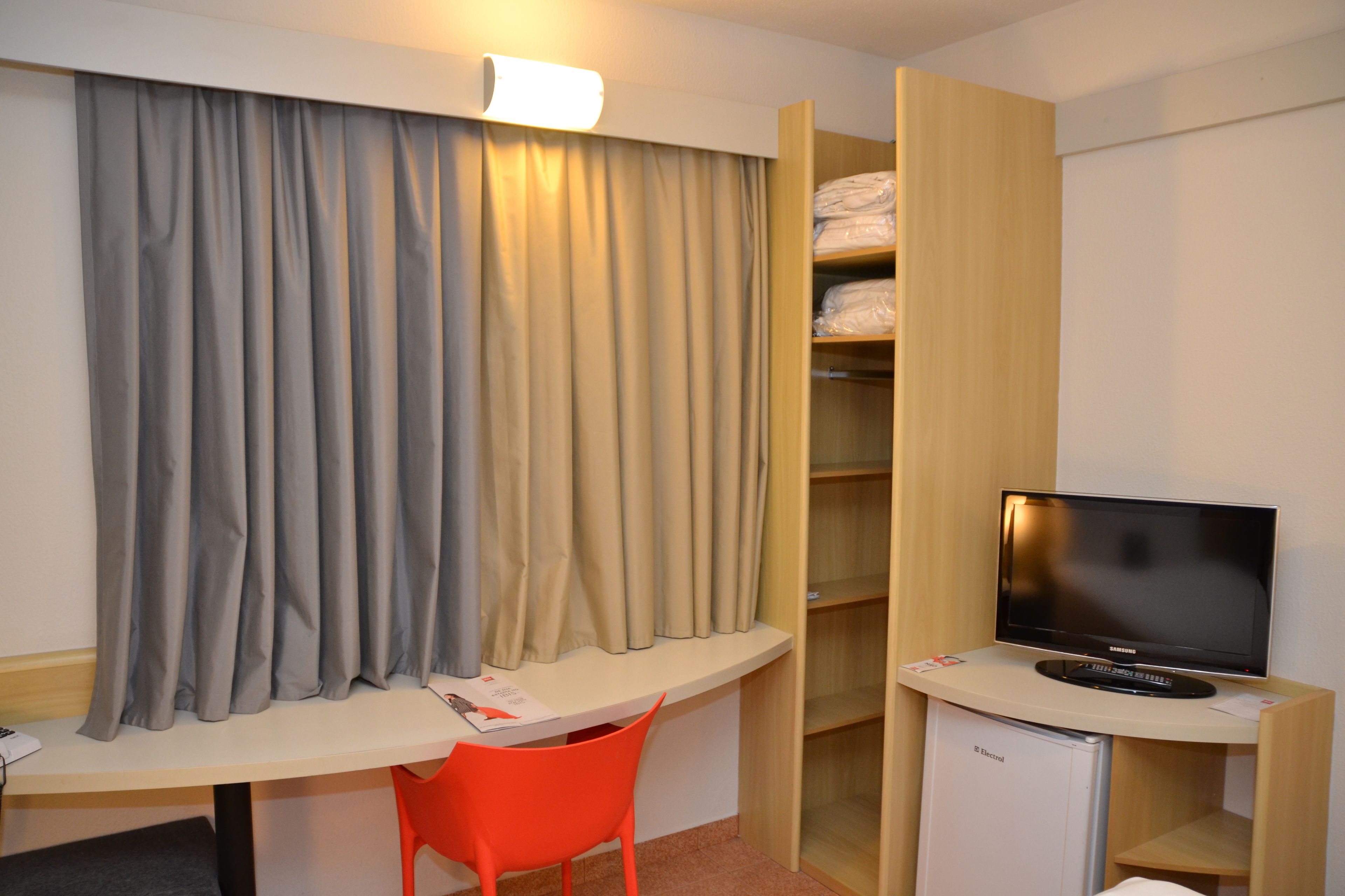 Una habitación de hotel con escritorio, televisión, armario y cama.