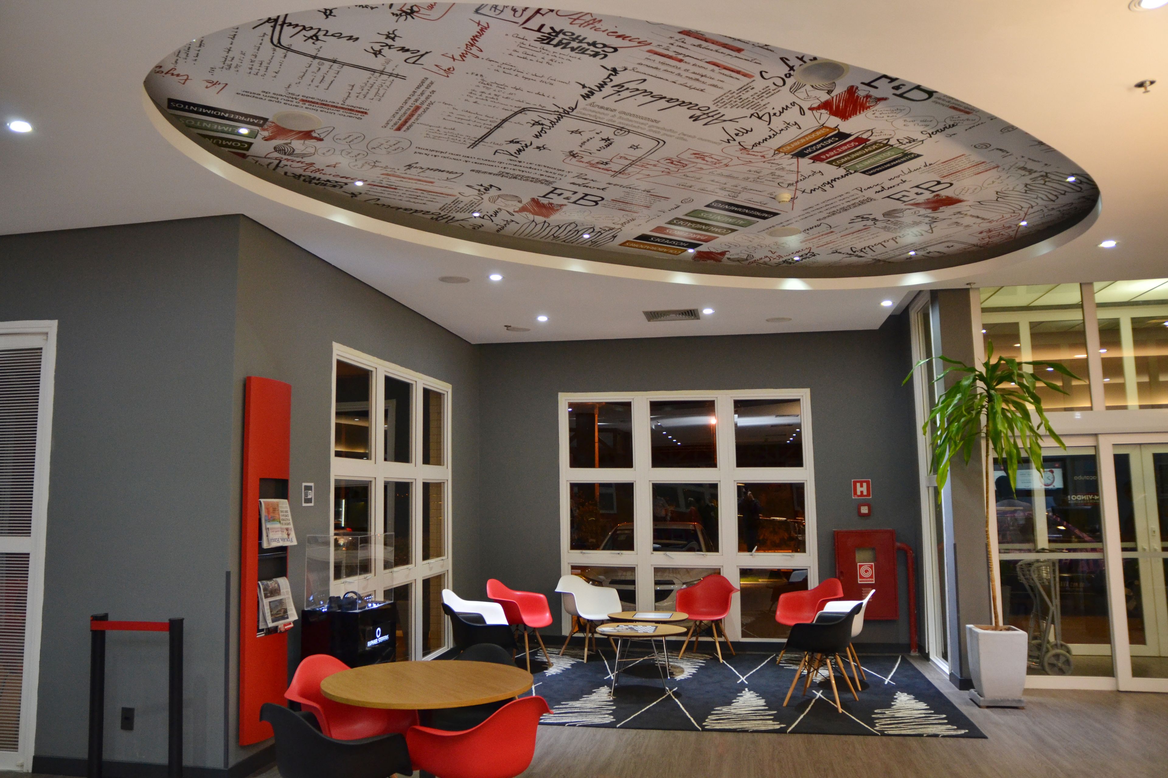 A modern conference room with a unique ceiling design, large windows, and a variety of seating options.