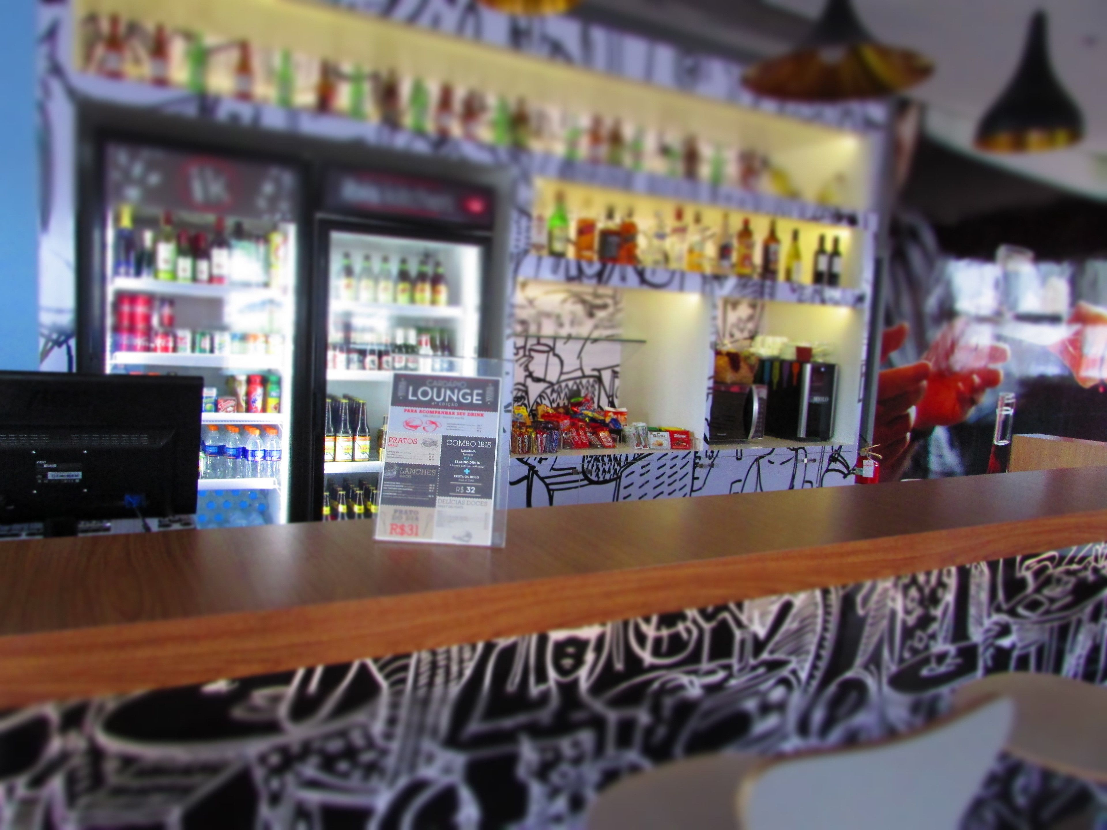 A bar area with a counter, a refrigerator stocked with beverages, and a menu board advertising the lounge and combo ibis.
