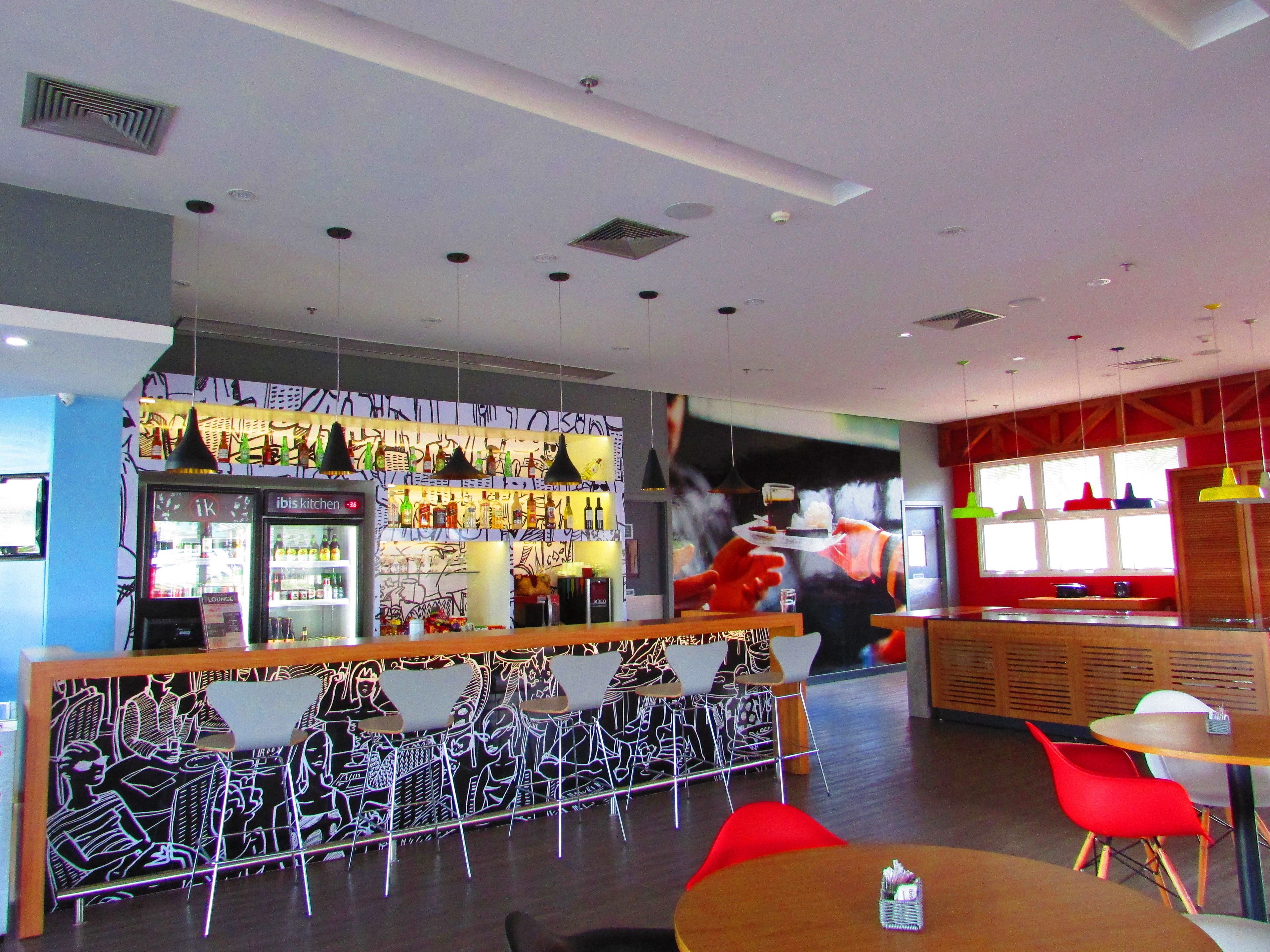 A modern restaurant interior with a bar area, seating, and a large mural.