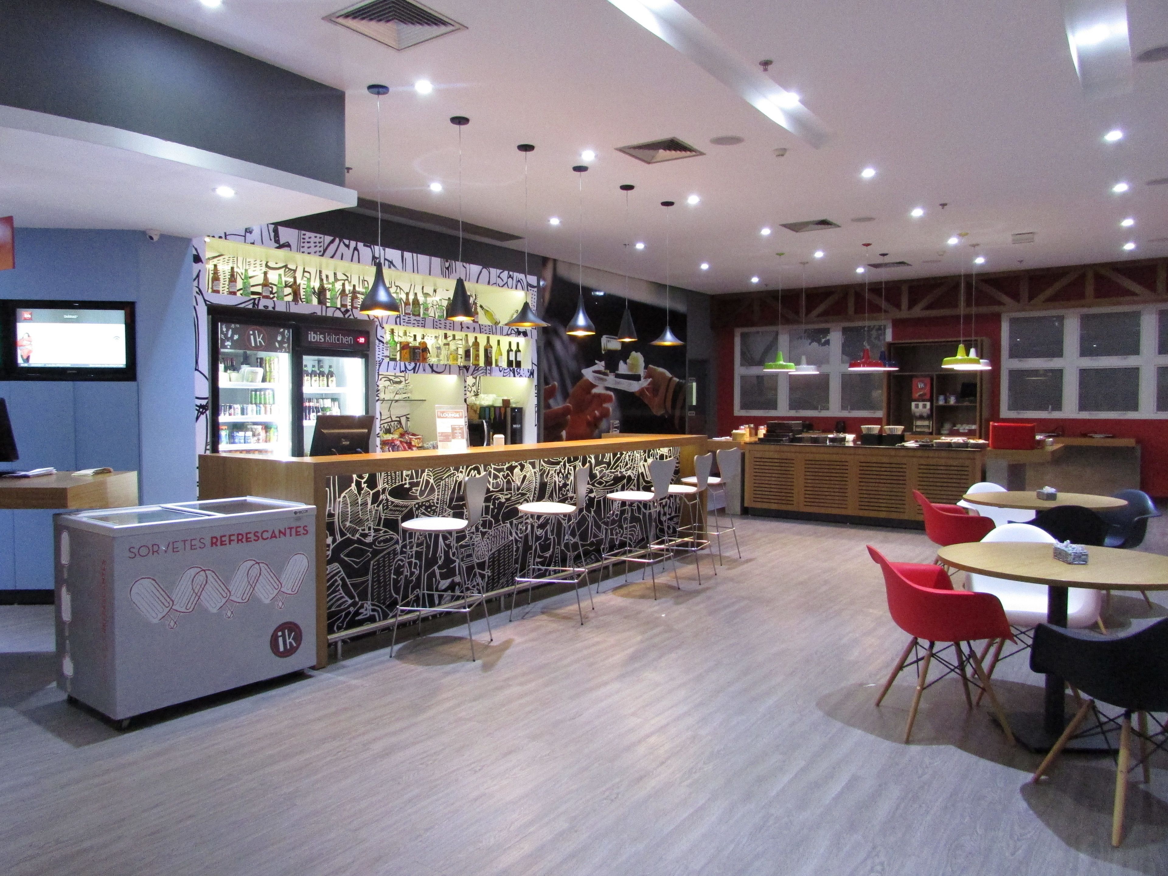 Zona de bar moderna con mostrador, asientos y un refrigerador que dice "Sorvètes Refrescantes".