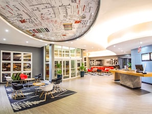 A modern hotel lobby with a reception desk, seating area, large windows, and a ceiling with a world map design. - ibis Aracatuba (Aracatuba)