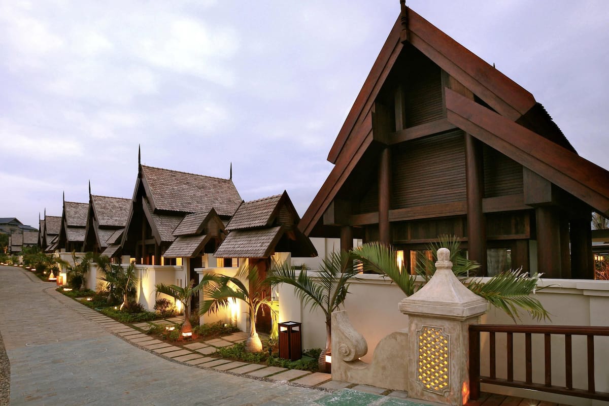 A row of traditional-style buildings with sloped roofs, a paved walkway, and decorative lighting.