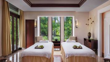 Relax in a serene space with two beds, a side table, and a view of lush greenery.