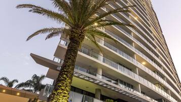 Un edificio alto con un letrero que dice "ARTIQUE" y una palmera frente a él.