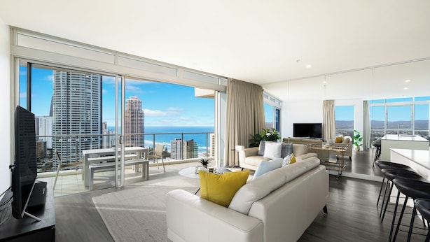 Ein modernes Wohnzimmer mit einer großen Couch, einem Essbereich und einem Balkon mit Blick auf die Stadt.