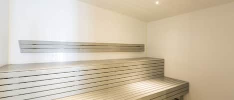 Una sauna con una panca a doghe e un poggiatesta in metallo.