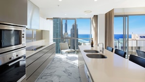 Eine moderne Küche mit einer großen Kochinsel, Edelstahlgeräten und Blick auf Stadt und Meer.