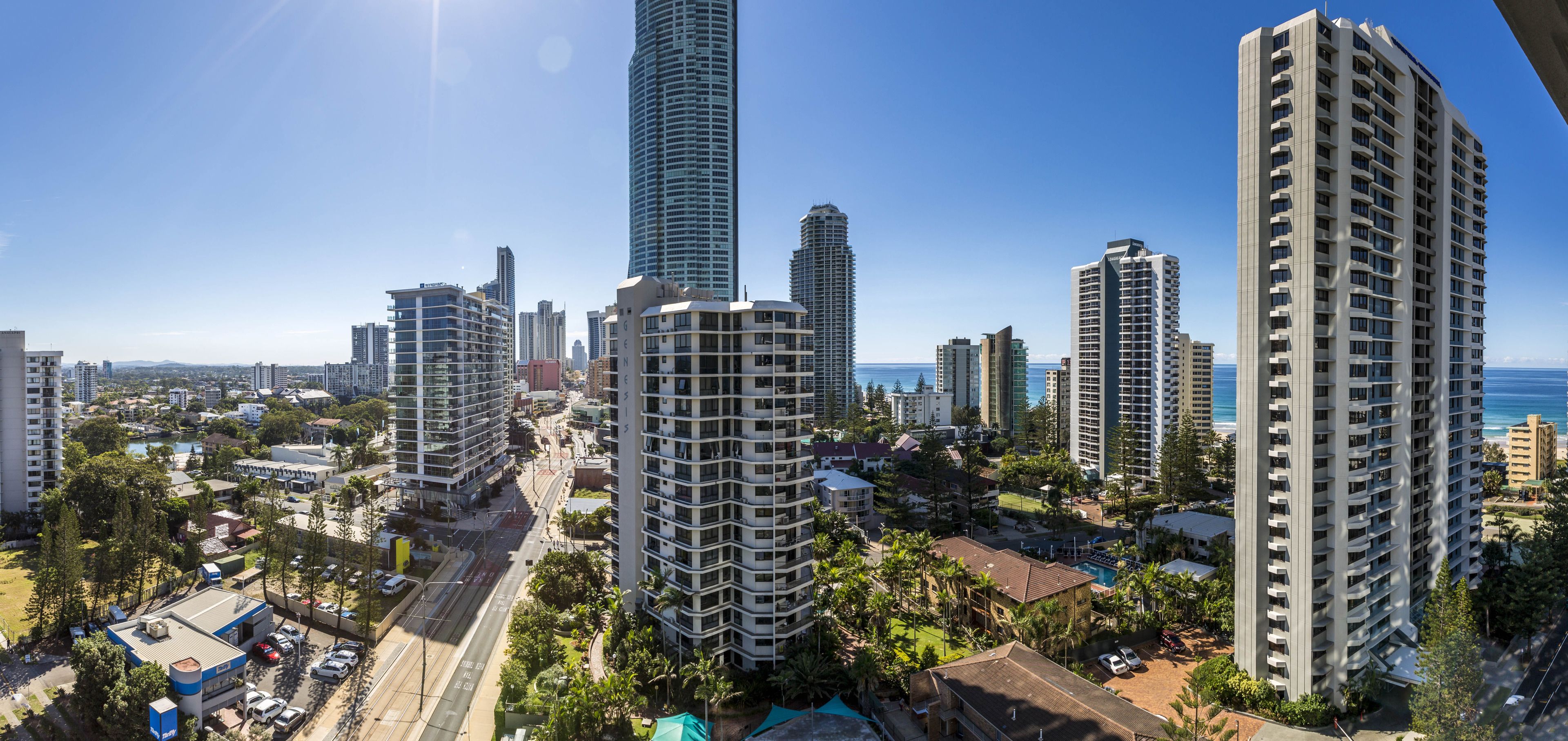 A high-rise building with a modern design, surrounded by other tall buildings and a clear view of the ocean.