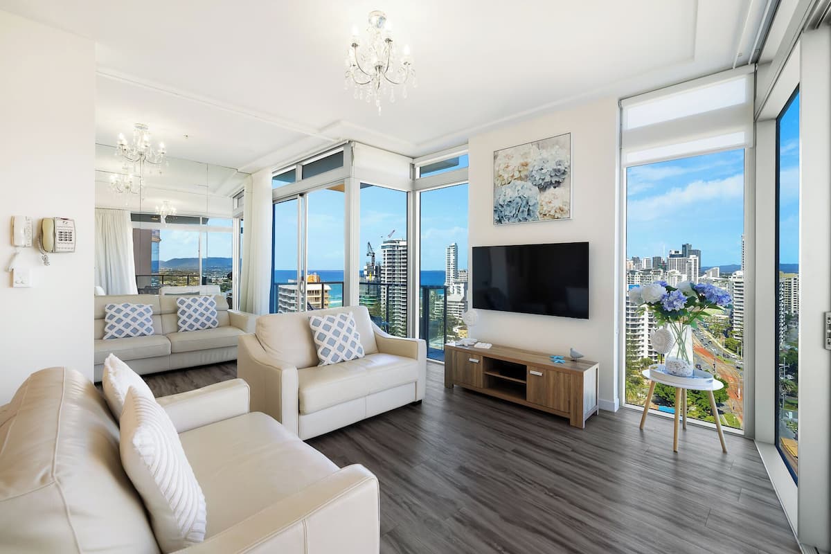 Een moderne woonkamer met een grote televisie, comfortabele zitmogelijkheden en uitzicht over de stad.