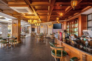 A bar area with wooden bar stools, a counter with taps, and a stone wall. - Saphir Hotel & Villas - All inclusive (Alanya)