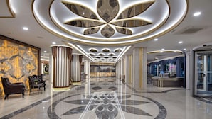 Eine moderne Hotelhalle mit Marmorboden, einer zentral platzierten Blütenleuchte und einem Empfangstresen.