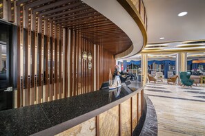 A modern hotel lobby with a curved reception desk, a seating area with plush chairs, and a marble floor. - Saphir Hotel & Villas - All inclusive (Alanya)
