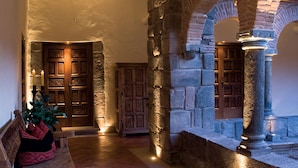 Un pasillo de paredes de piedra con un banco de madera y una puerta.