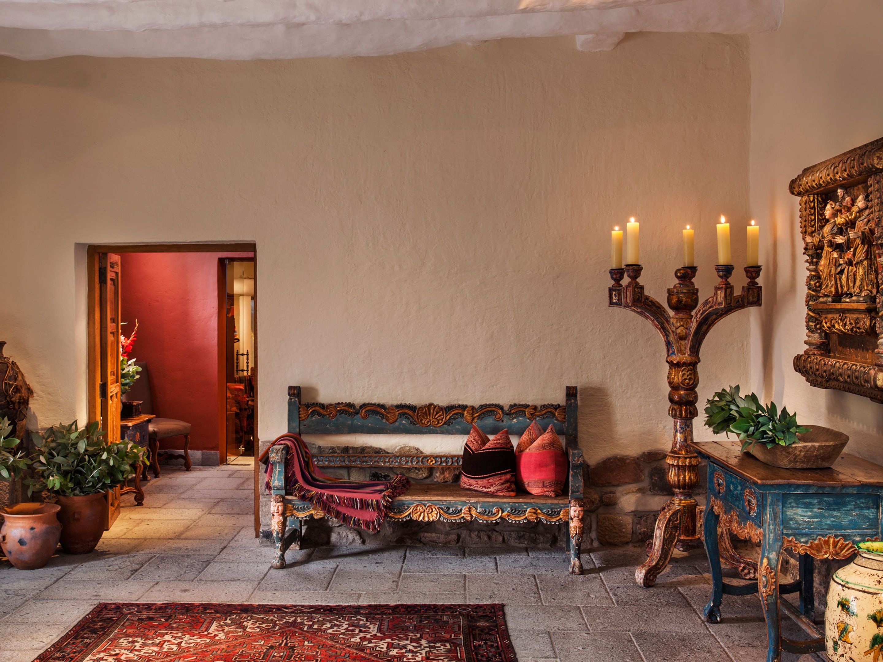 A traditional room with a bench, a candelabra, and a decorative wall piece.