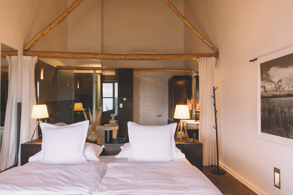 Un dormitorio con cama a dosel, un espejo grande y vistas al baño.