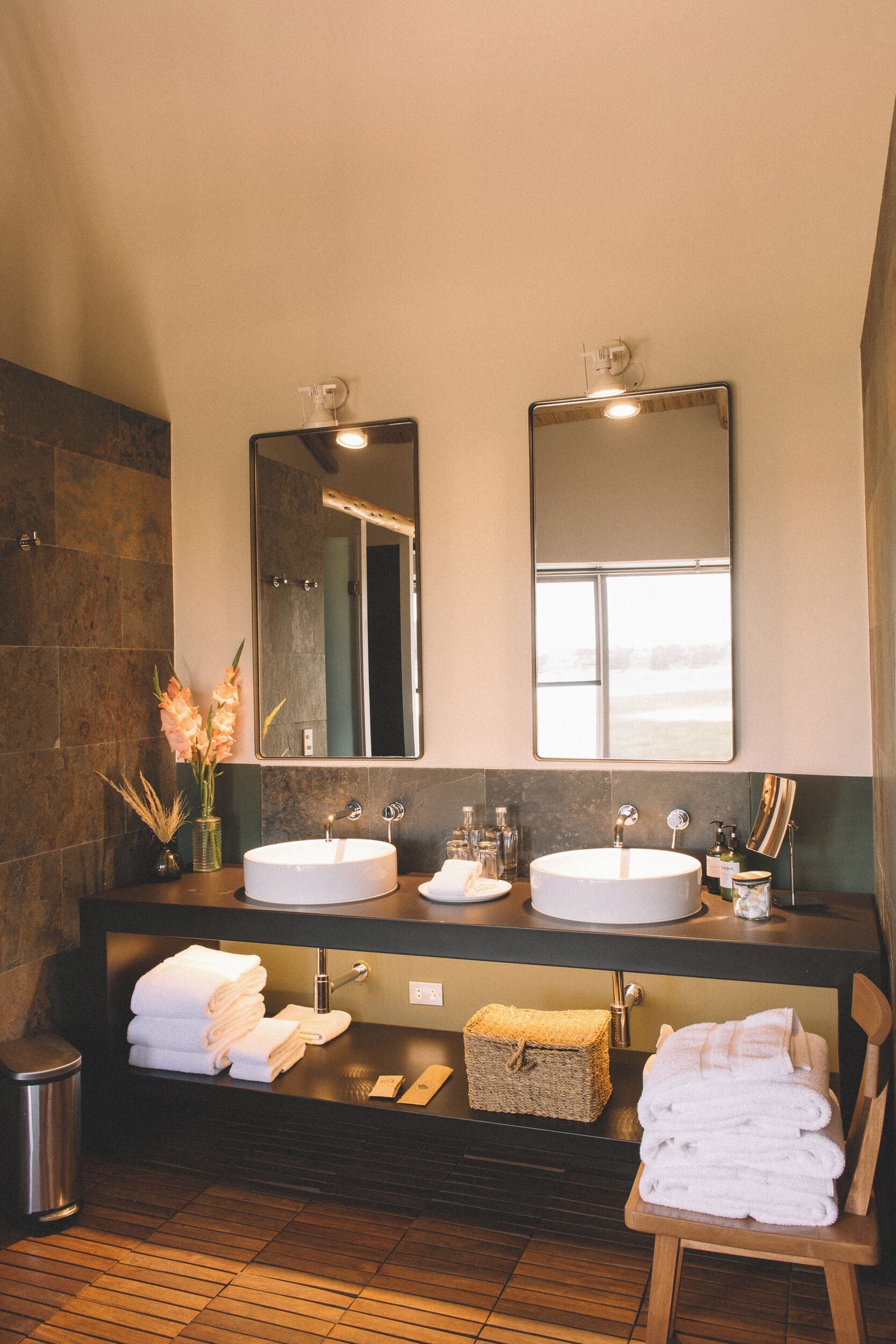 Un baño moderno con dos lavamanos, un espejo grande y vistas al exterior.