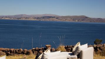 A seating area with a view of a large body of water and distant hills.