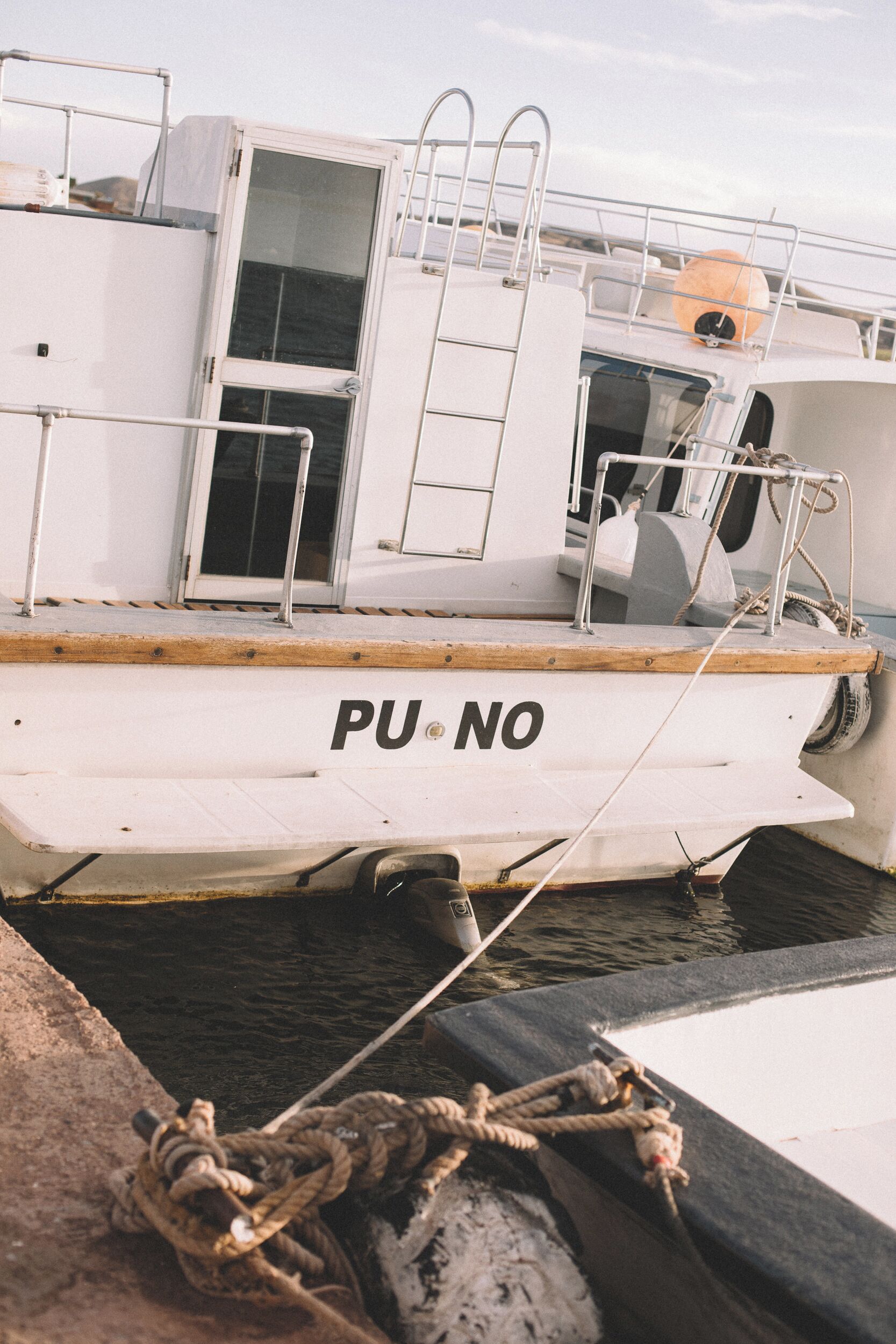 Um barco atracado em um cais, com cabine e área de convés visíveis.