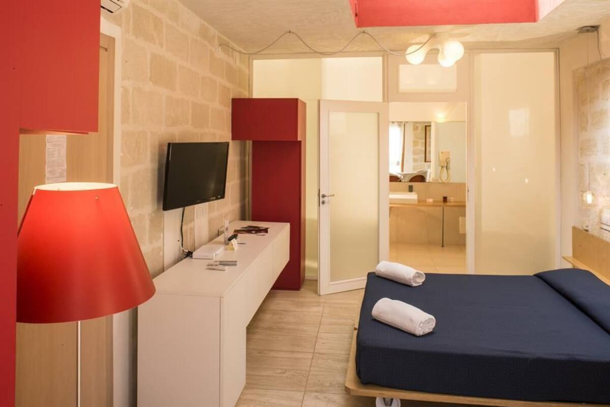 Une chambre d’hôtel avec un lit, une télévision, un bureau et un miroir.