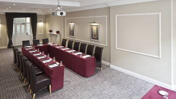 A conference room with a long table, multiple chairs, and a projector.