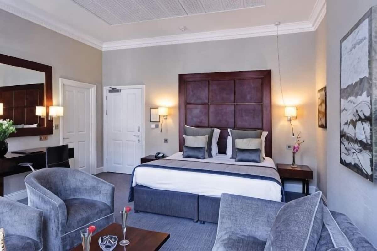 A hotel room with a large bed, two bedside tables, a desk, and a chair.