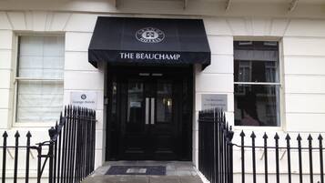 The entrance to The Beauchamp, a hotel with a black awning and a sign indicating its name and address.