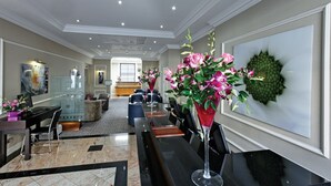 A spacious lobby with a long reception desk, seating area, and a large wall-mounted artwork. - Grange Beauchamp (London)