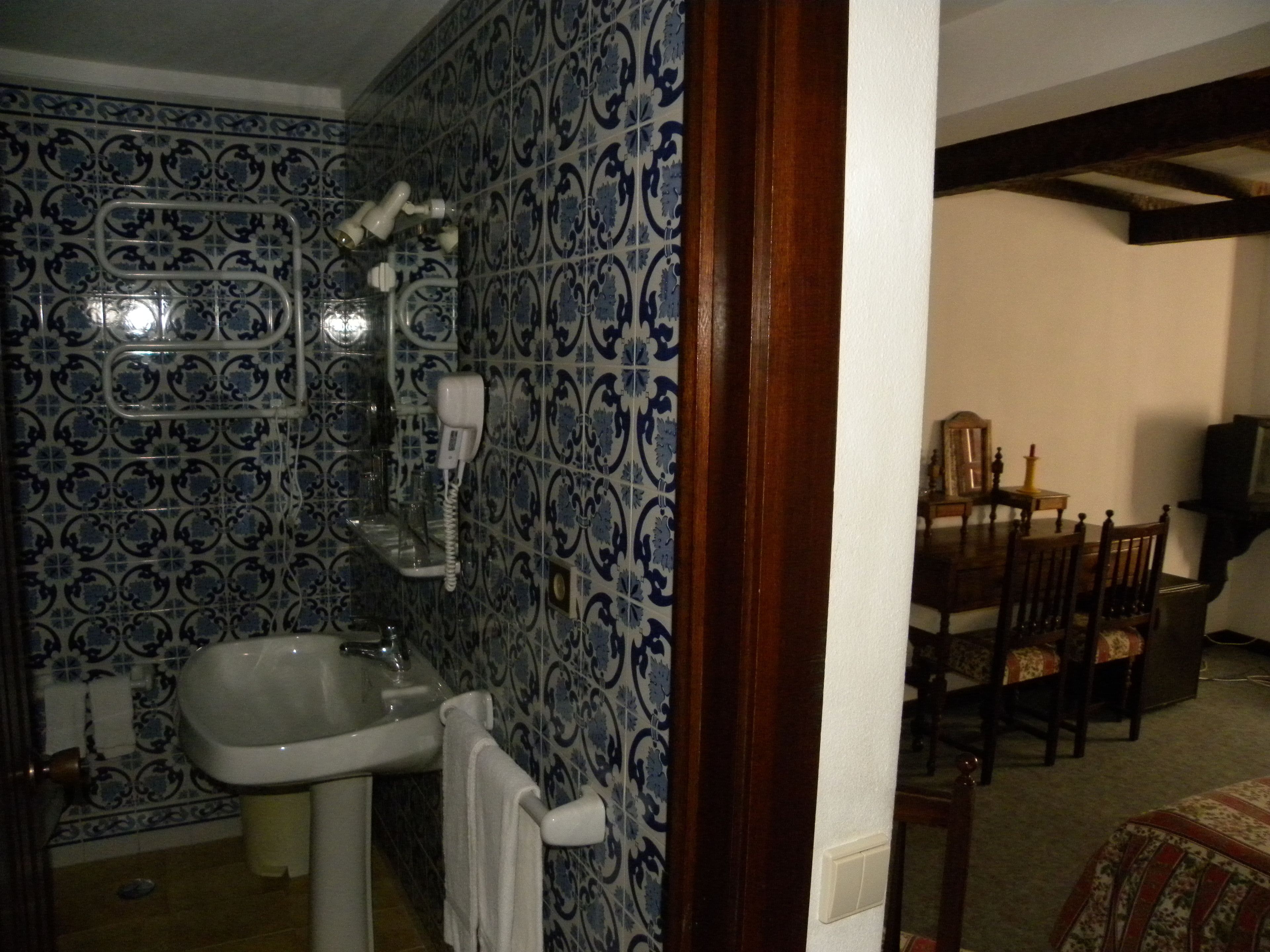 A bathroom with a sink, towel rack, and a shower area with a white hose.