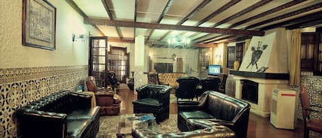 Una sala de estar tradicional con sofás de cuero, una chimenea y un televisor.