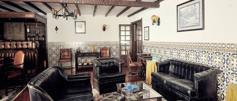 A traditional interior with leather furniture, patterned walls, and exposed wooden beams.