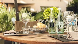 A round wooden table with a bottle of Il Corniolo Ristorante, a glass of water, a glass of wine, a basket with bread, and a napkin. - Best Western Plus Hotel Le Favaglie (Cornaredo)