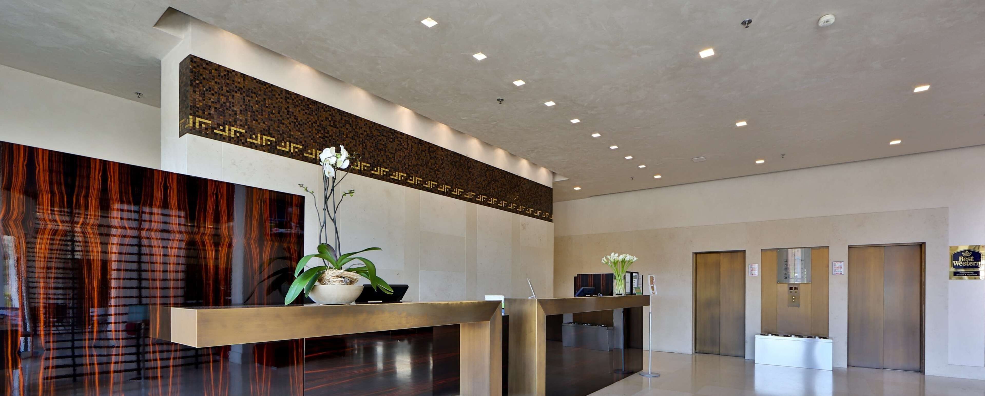 Un área de recepción de diseño moderno, con mostrador de recepción, una pared decorativa y un ascensor.