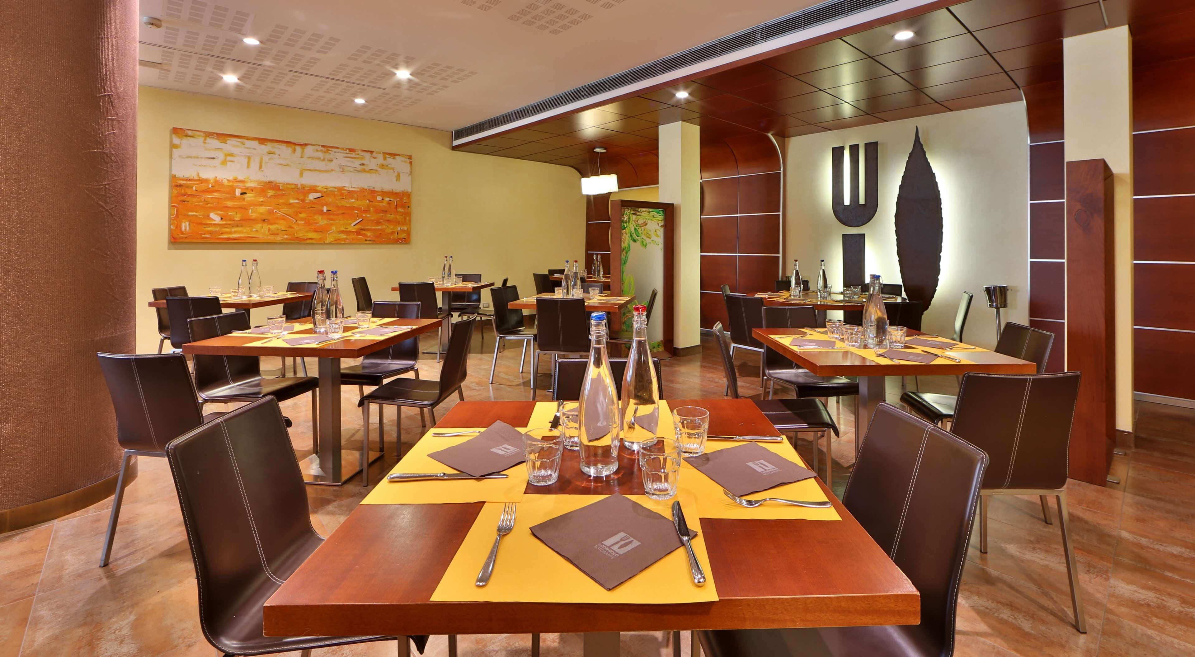Un restaurante con varias mesas, cada una dispuesta con cubiertos, servilletas y botellas de agua.