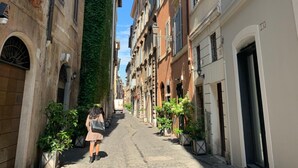 A narrow cobblestone street flanked by historic buildings with a mix of architectural styles, including a building with a green vertical garden. - Residenza Domizia- Guest House (Rome)